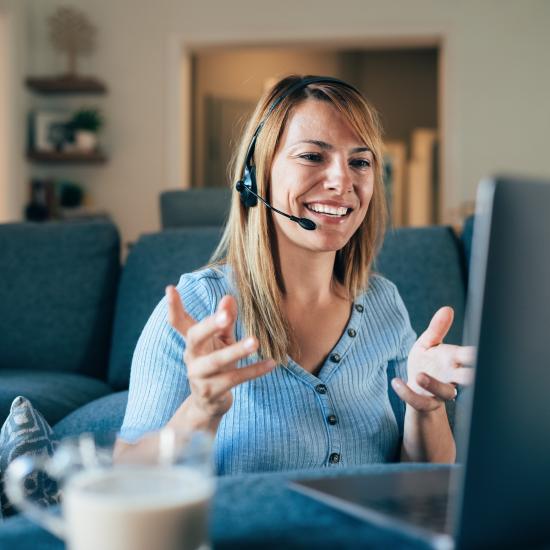 Woman speaking on a call with a headset on in front of a laptop