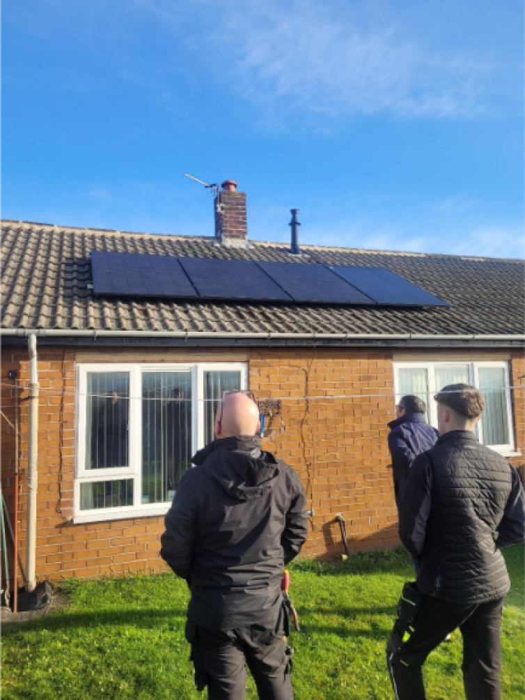 The Berneslai Homes electrical team, and Andy Heald, director at Energise Barnsley looking at solar panels installed on the roof of a house.