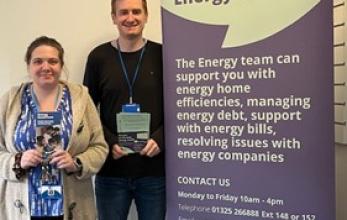 Two Energy Advisers at Citizens Advice Darlington Redcar and Cleveland standing next to an information banner.