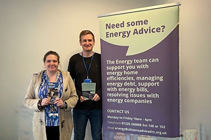 two people standing with a banner that reads: need some energy advice?