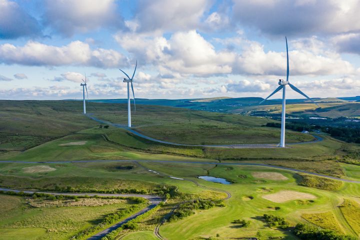 aerial drone shot of several clean energy wind turbines in a rural area of Wales