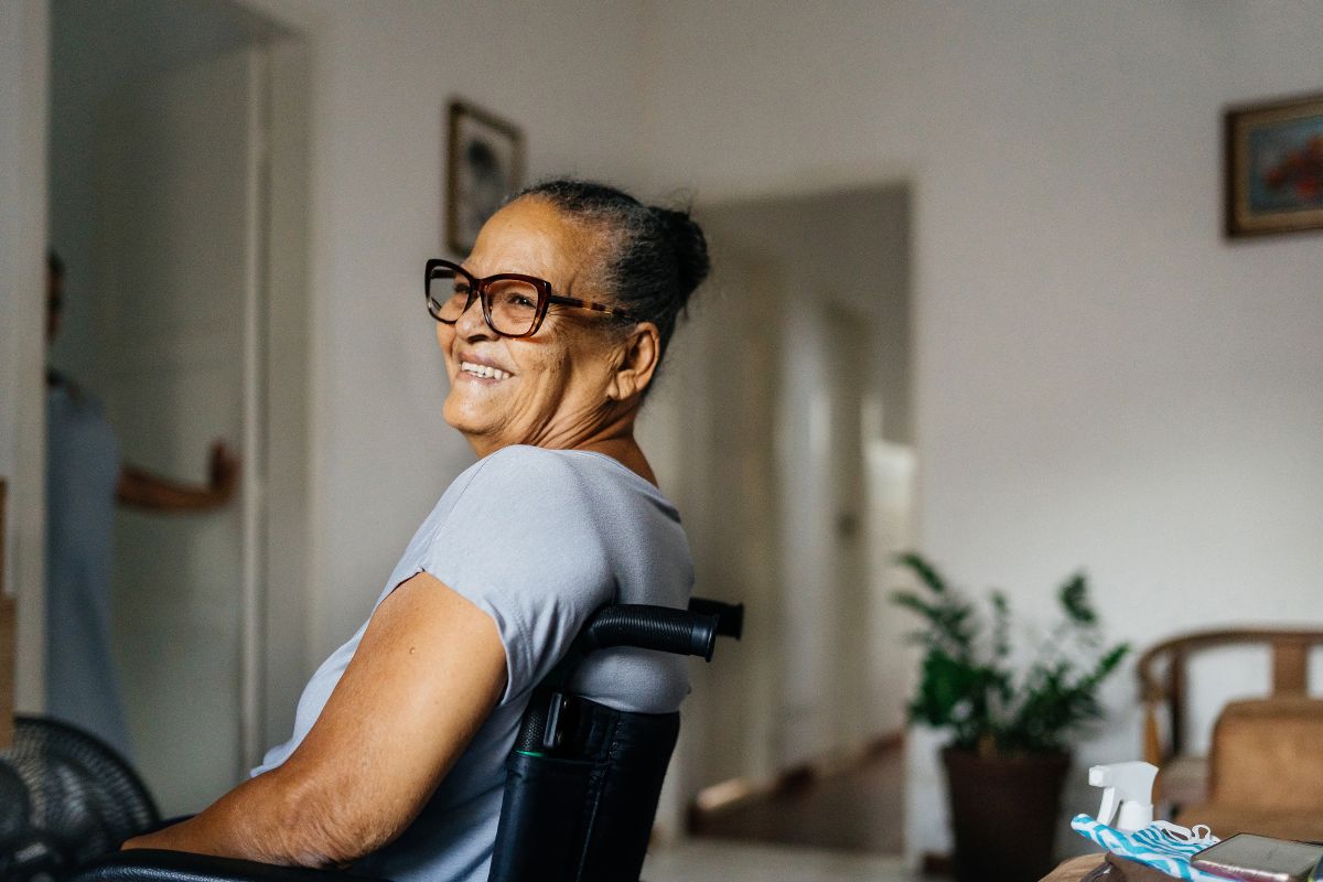 smiling senior woman in a wheelchair in a comfortable room with chairs and a plant