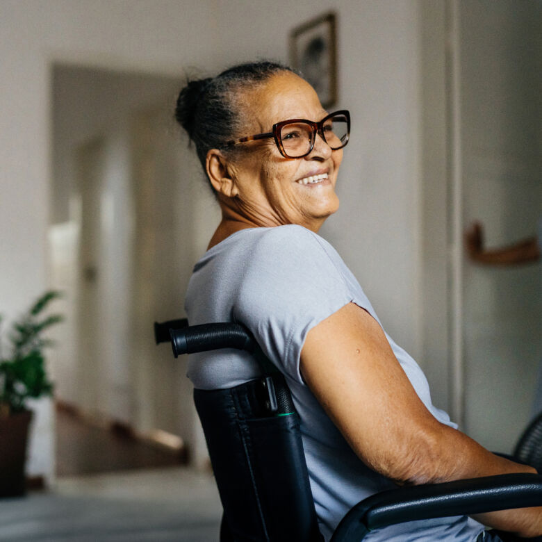 smiling senior woman in a wheelchair in a comfortable room with chairs and a plant